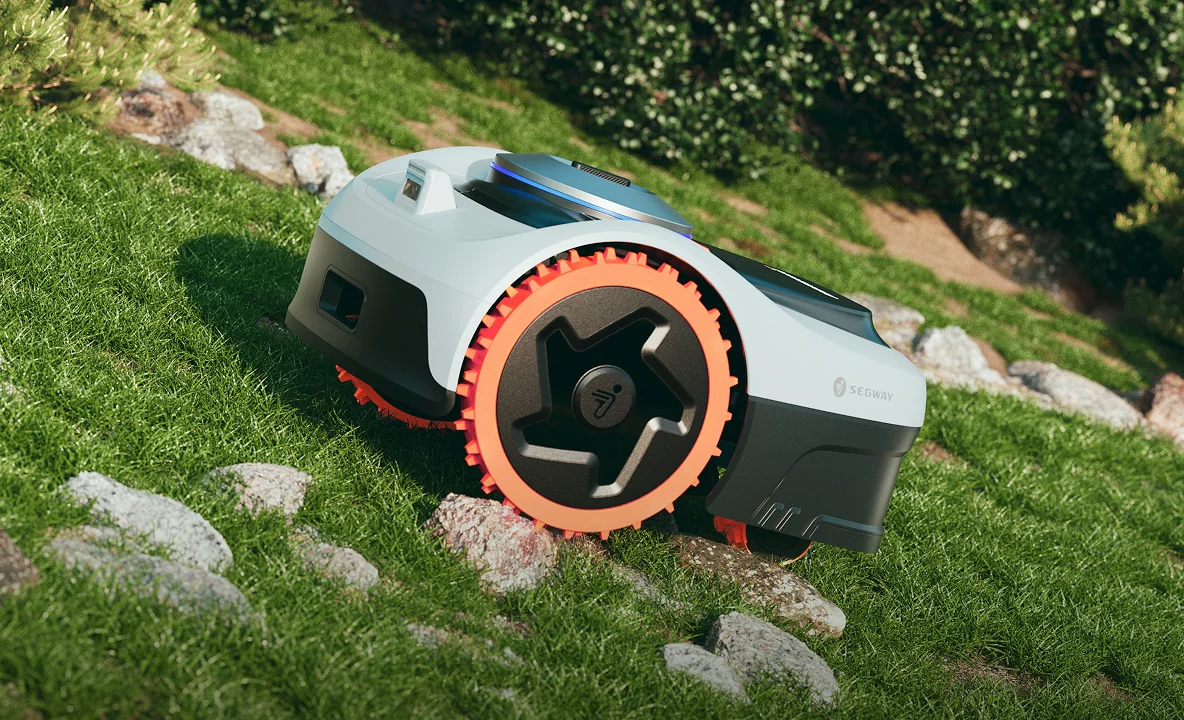 Een Segway Navimow robotmaaier rijdt moeiteloos over een grashelling met stenen in een moderne tuin.