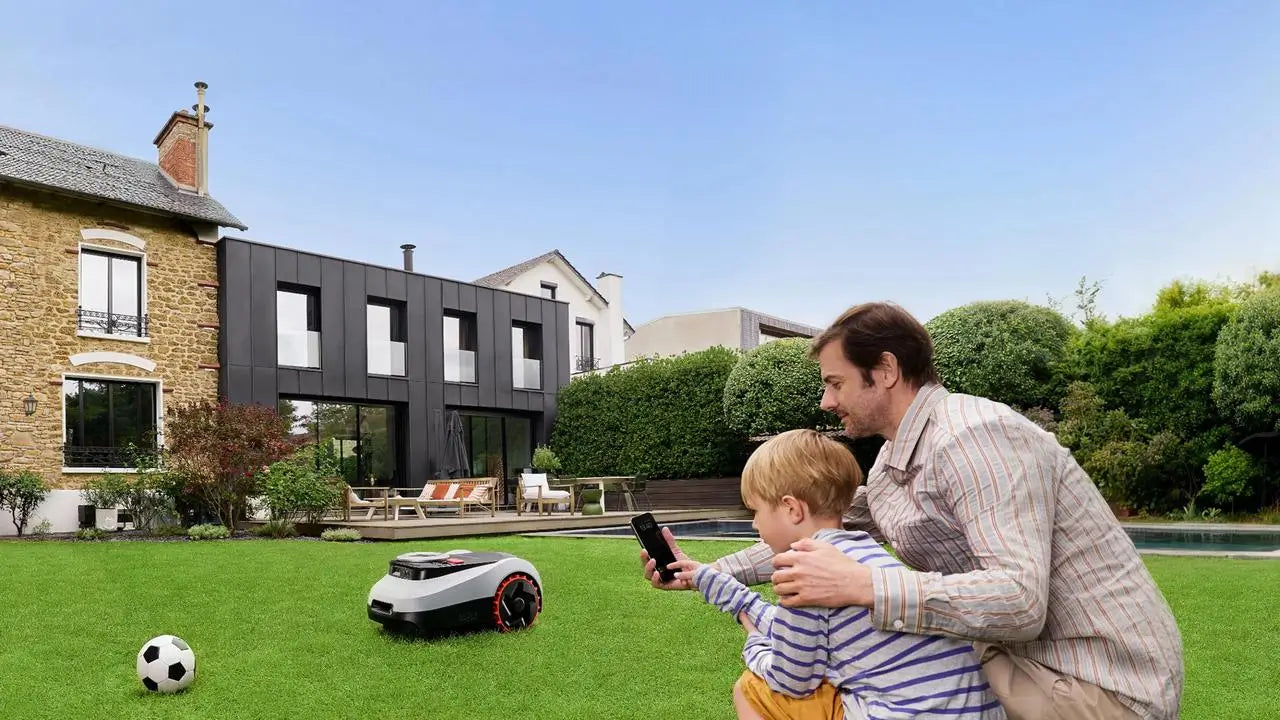 Vader en kind bedienen de draadloze Navimow robotmaaier eenvoudig met een smartphone in de eigen achtertuin.