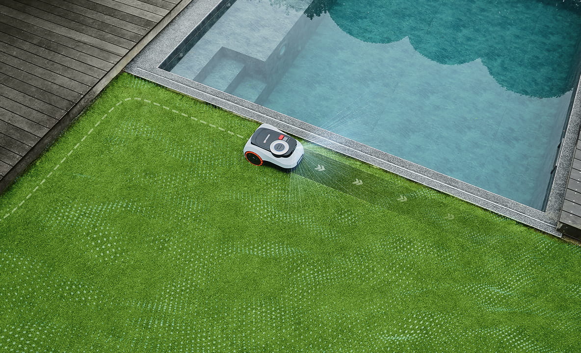 Navimow i105E robotmaaier maait het gras naast een blauw zwembad.